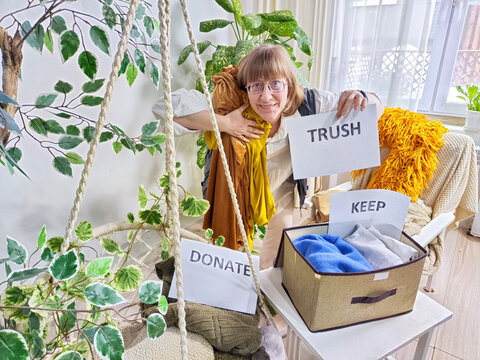 Middle-Aged Woman Sorting Belongings With KonMari Method. Mature woman categorizes items into keep and discard piles