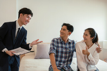 Couples young considering buying a home, investing in real estate. Broker signs a sales agreement....