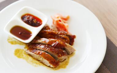 Close up roasted ducks with two types of sauce in a small white plate, small portion of roasted ducks, Asian popular menu originally from China.