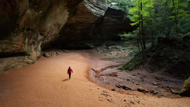 Female Hiker Wonders Hocking Hills Ash Cave Magical Aerial Forest Trail Scenic View. Drone Up to Waterfall Overhang.