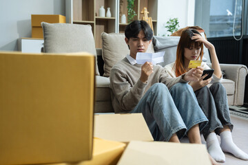 Exhausted couple sit rest on sofa in living room near heap of cardboard boxes feel unmotivated to unpack their belongings. Financial problem, debt and eviction, house debt bankrupt stress concept