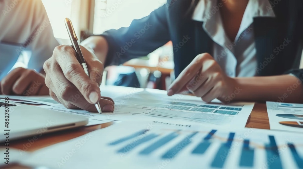 Poster A financial advisor consulting with a client, pointing at a document with investment options and financial charts.