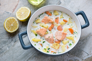 Serving pan with finnish traditional salmon soup lohikeitto, horizontal shot on a grey granite background, elevated view