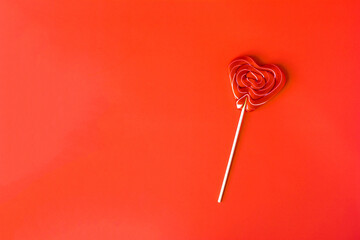 A red lollipop on a red background of a copy space.