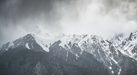 Panorama of mountain range of rocks with snow and glaciers in Pamir in Tajikistan mountains in cloudy weather, minimalistic landscape of high mountains for background
