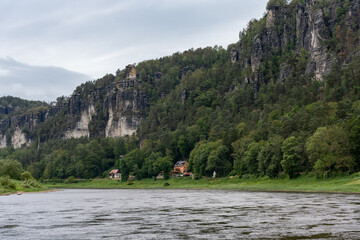 A mountain range with a river running through it. The water is calm and the trees are lush and green
