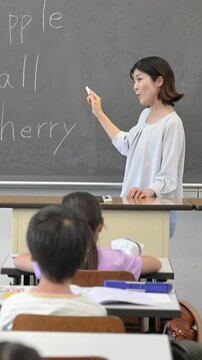 English class in a Japanese elementary school classroom Vertical video of teacher and children without faces	