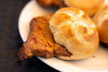 A piece of meat is on a plate next to a bun