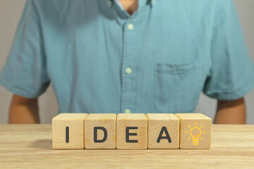 IDEA word written on wooden blocks and light bulb icon. Business idea concept with innovative...