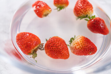 Preparing Strawberries in a Glass Mixing Bowl with Water