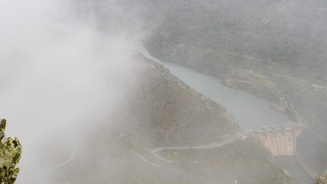 Mountain and Douro river with spanish Saucelle Dam at foggy cloudy weather. Border between Portugal and Spain. National Parks. View from portuguese Penedo Durao lookout.