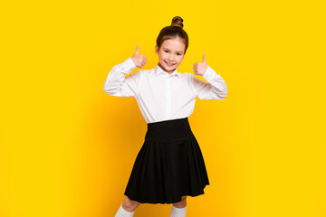 Photo of cute schoolgirl show thumb up wear uniform isolated on yellow color background