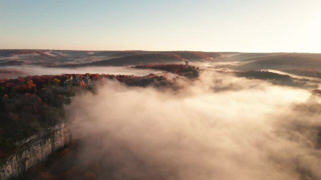 Epic Castle on Hill Cliff Edge Fantasy Fog Low Clouds Dramatic Landscape. Sunrise Rays Across Ancient Medieval Castle Ruins Ha Ha Tonka Missouri.