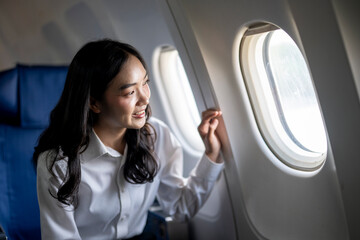Fototapeta premium A woman is sitting in an airplane and looking out the window