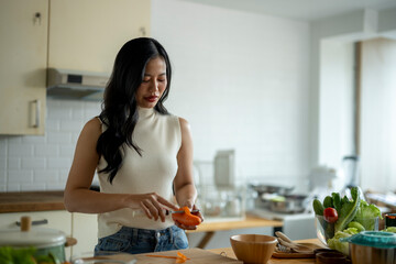 A woman is cutting an orange in a kitchen