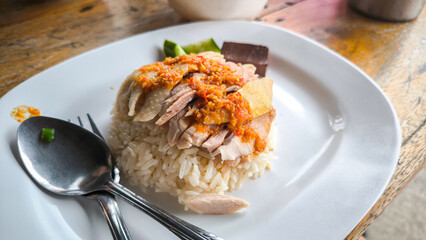 Hainanese chicken both steamed and fried chicken served with Hainanese oily rice, dipping sauces, and chicken clear soup. Thai famous Street food.