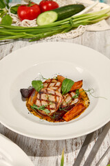 Grilled Pork Medallions with Baked Vegetables and Fresh Summer Produce on Wooden Table in Sunlight
