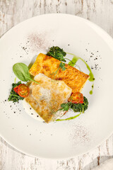 Battered Pike Perch with Potato Gratin in Sunlit Setting on Wooden Table