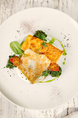 Sunlit Fried Pike Perch with Potato Gratin on Rustic Wooden Table