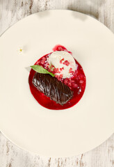 Chocolate Potato Pastry with Ice Cream and Raspberry Sauce in Sunlight on Wooden Table