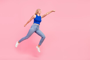 Full size photo of pretty young woman jump fly empty space wear blue top isolated on pink color background