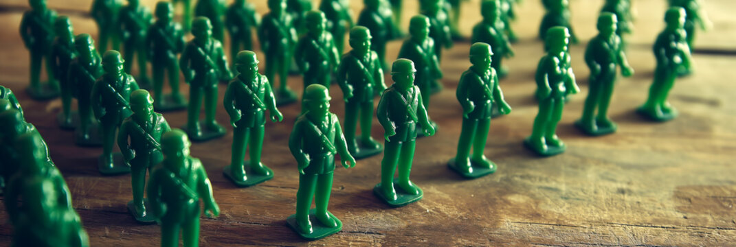 Vintage-style photo of an array of green plastic toy soldiers lined up for an imaginary parade on wooden surface.