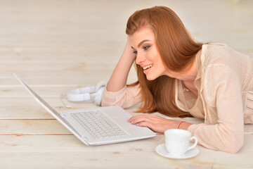 Adult beautiful woman lying on floor with laptop