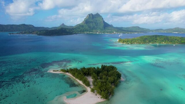 Aerial view of turquoise lagoon with remote island and scenic mountain, Motu Tapu, Bora Bora, French Polynesia.