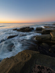 Beautiful morning pastel sky over rocky coastline.
