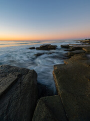 Beautiful morning pastel sky over rocky coastline.