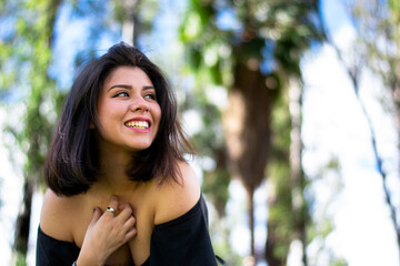 Fototapeta premium 20s beautiful hispanic woman smiling, low angle, she is content in a park looking away. Concept of freedom. 