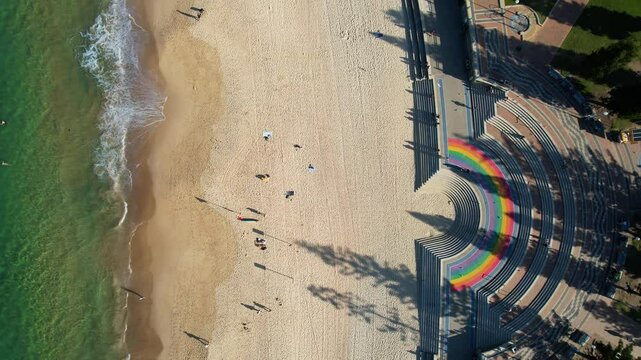 Aerial view of Coogee Beach Rainbow Walkway with swimmers and beachgoers, Sydney, Australia.