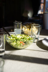green salad served on white table, table ready for lunch vertical view