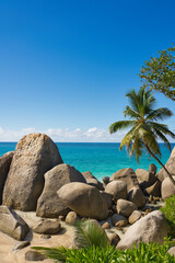 Carana beach view from the road, blue sky turquoise water, low tide with waves, sunny day, white sandy beach, coconut trees, huge granite stones, Mahe, Seychelles 