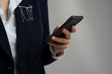 Woman in chic attire with smartphone, hand on hip, ready for corporate event