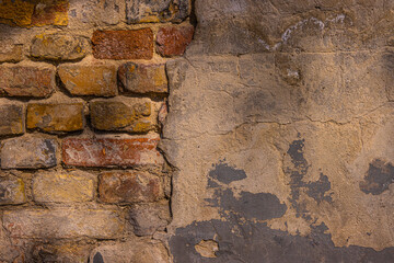 Old damaged broken shabby red brick wall of an old building. Brick texture with scratches and cracks. Grunge background with cracked grey blueish stucco.  Close up. Copy space