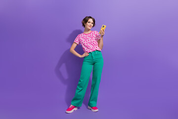 Full body photo of attractive young woman hold telephone eshopping wear trendy pink clothes isolated on purple color background