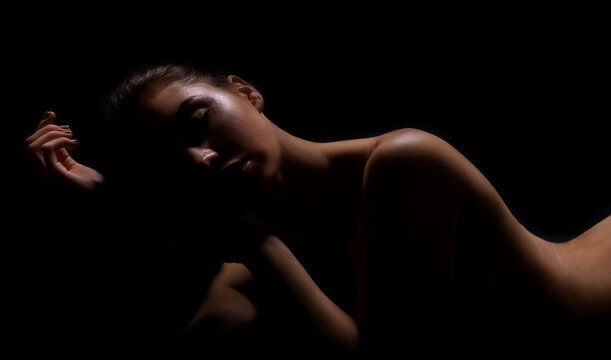 This is a photo of a woman posing in silhouette against a dark background. Her body is partially visible, with her face and shoulders illuminated by a soft light.