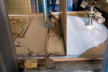 Foam rubber production, sponge production, foam production. White liquid flows from a pipe onto a conveyor belt