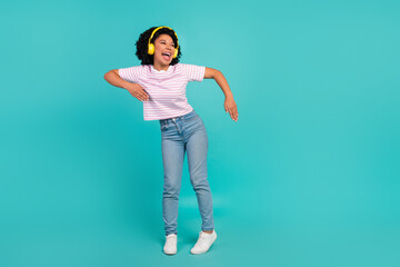 Photo of funny youth girl with curly hair enjoying music her new stereo headphones dance like robot isolated on cyan color background