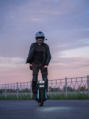 A man rides a monocycle on the sidewalk. Mobile urban transport. Rider In helmet, gloves and knee pads © pavelkant