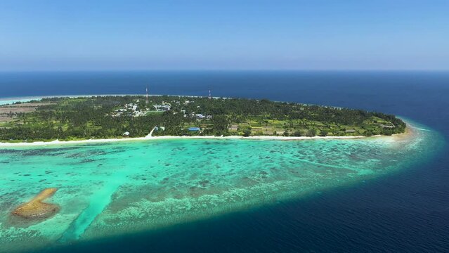 Aerial view of turquoise lagoon with coral reefs and local island houses, Thoddoo Atoll, Maldives.