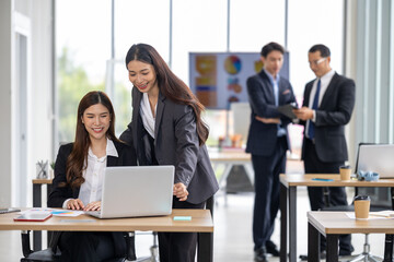 Professional and driven, two Asian businesswomen are seen collaborating in a contemporary office space, highlighting their commitment to effective business planning and partnership 