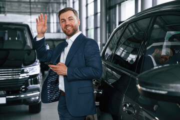 Hello hand gesture. A businessman is in a car dealership