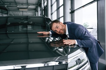 Embracing new automobile. A businessman is in a car dealership