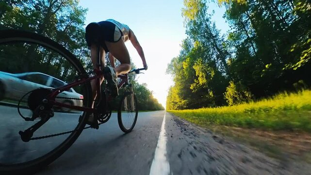 Young man cycling on the asphalt empty road at sunset