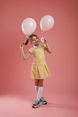 Fototapeta premium Donut in hand. Cute little girl is against pink background