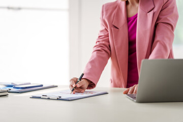 40-year-old middle-aged Asian businesswoman wearing pink suit, business finance, investment strategies, risk management. Skilled in planning, analysis, operations control for business success.