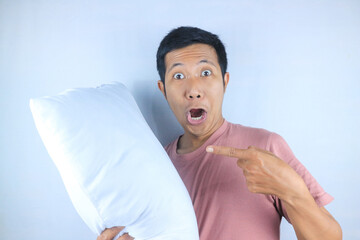 Excited facial expression of young Asian man hug a pillow, preparing to sleep. Bedtime concept