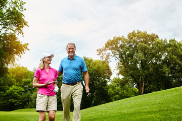 Mature, couple and walking on golf course, outside and healthy fitness activity with golfers together with club. Relaxing, weekend break and happy with smile for sport, nature exercise and people